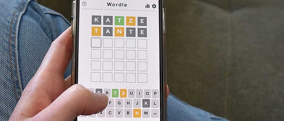 Hand hält Handy und tippt Buchstaben in Quiz
